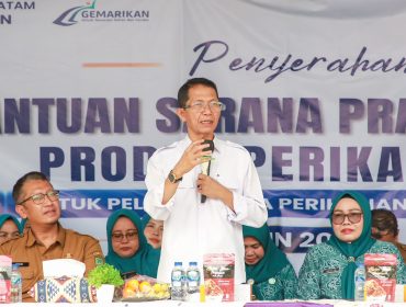 Wali Kota Batam, Amsakar Achmad, didampingi Ketua TP-PKK Batam, Erlita Amsakar, dan Kepala Dinas Perikanan Kota Batam, Yudi Atmajianto, menyampaikan sambutan saat penyerahan bantuan sarana dan prasarana kepada kelompok pengolah dan pemasaran hasil perikanan di Sagulung, Senin (14/9/2026). 