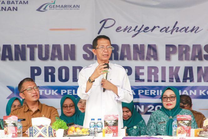 
					Wali Kota Batam, Amsakar Achmad, didampingi Ketua TP-PKK Batam, Erlita Amsakar, dan Kepala Dinas Perikanan Kota Batam, Yudi Atmajianto, menyampaikan sambutan saat penyerahan bantuan sarana dan prasarana kepada kelompok pengolah dan pemasaran hasil perikanan di Sagulung, Senin (14/9/2026). 